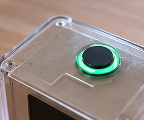 Top of the box: a single large green button, lit from within.